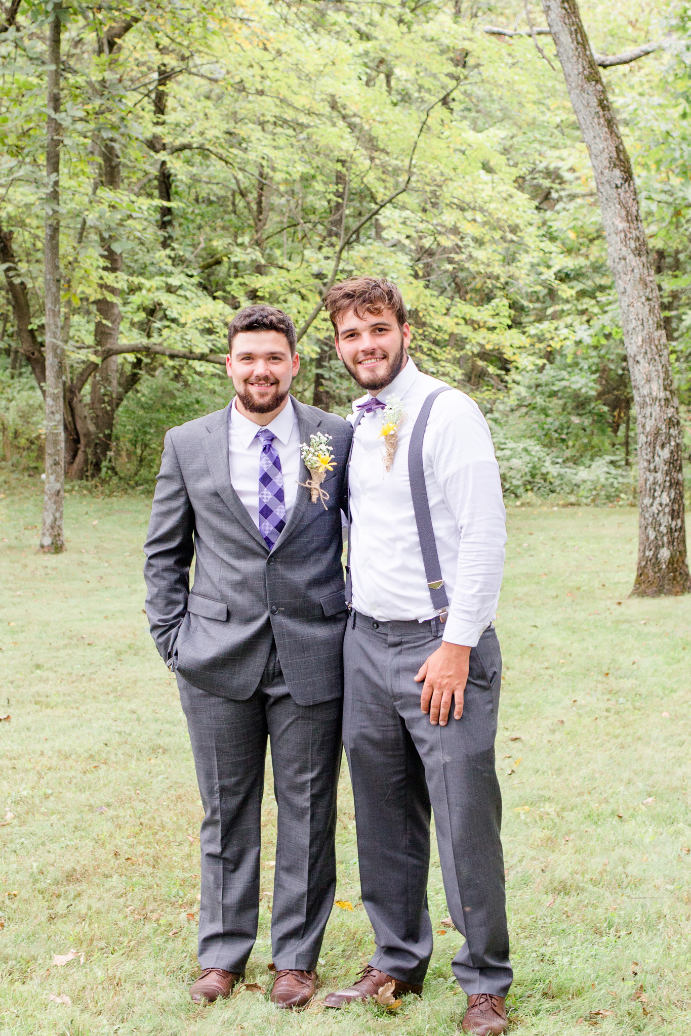 Grooms gray suit with purple plaid tie and groomsmen with suspenders